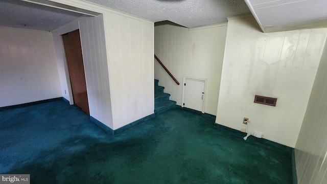 carpeted spare room with a textured ceiling and wood walls