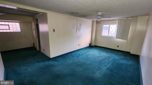 unfurnished room with ceiling fan, a textured ceiling, and dark colored carpet