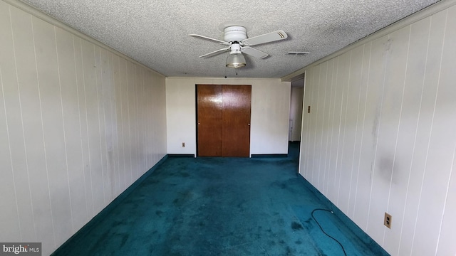 carpeted spare room featuring a textured ceiling and ceiling fan