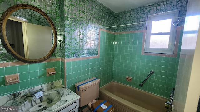 full bathroom with tile walls, vanity, tiled shower / bath combo, and toilet