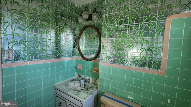 bathroom featuring tile walls, vanity, and toilet