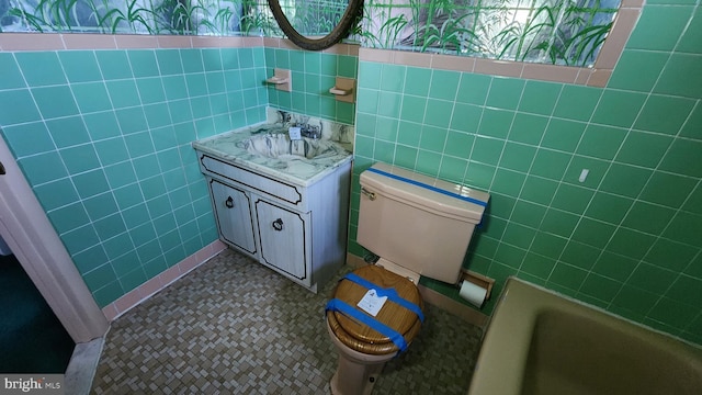 bathroom featuring tile patterned floors, vanity, toilet, and tile walls