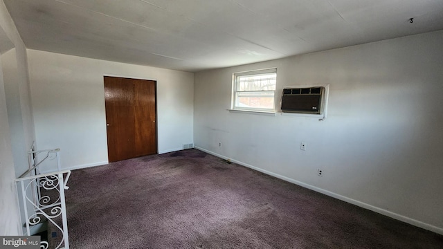 spare room featuring dark carpet and a wall unit AC