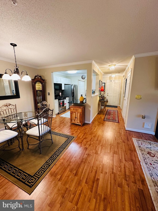 unfurnished dining area with a chandelier, light wood-type flooring, a textured ceiling, and crown molding