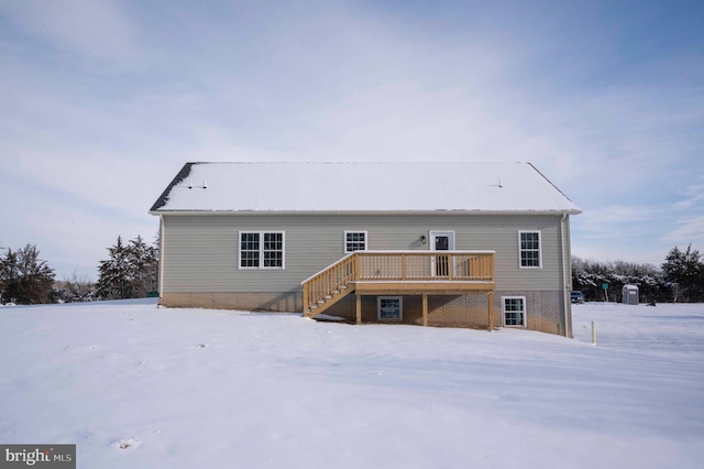 snow covered back of property featuring a deck