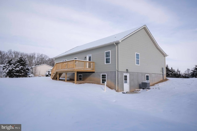 snow covered rear of property with central air condition unit and a wooden deck