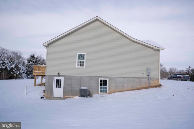 view of snow covered exterior featuring a wooden deck and central AC unit