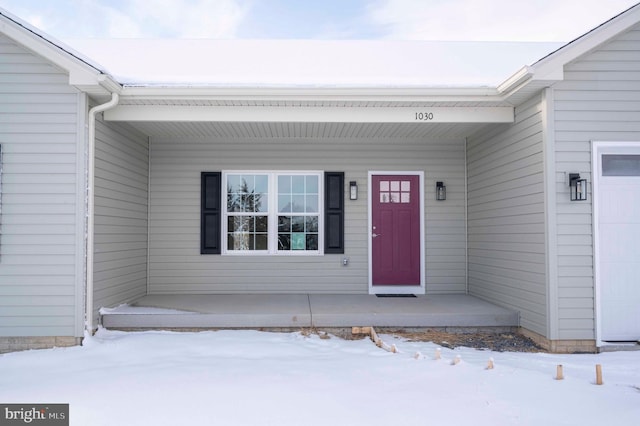 snow covered property entrance with covered porch