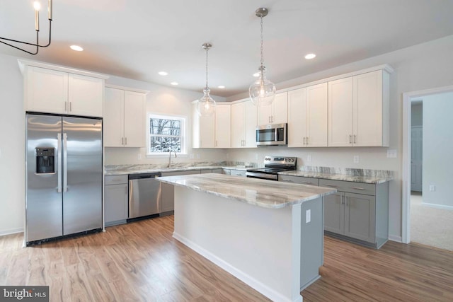 kitchen featuring white cabinets, a center island, hanging light fixtures, and appliances with stainless steel finishes