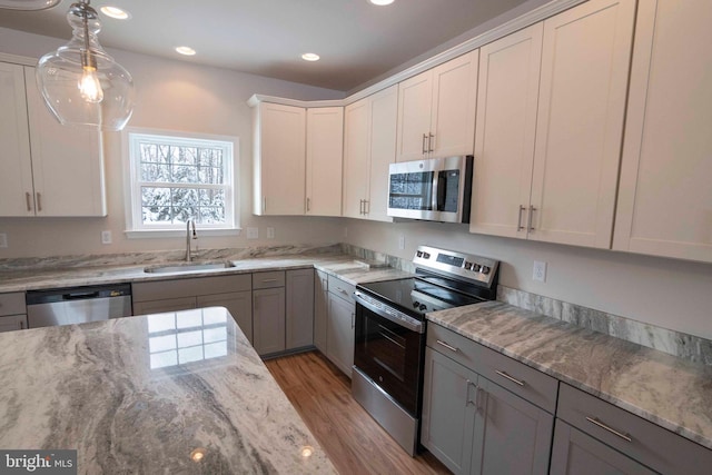 kitchen featuring appliances with stainless steel finishes, sink, white cabinets, pendant lighting, and gray cabinets