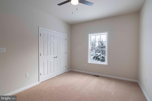 unfurnished bedroom with a closet, ceiling fan, and light carpet