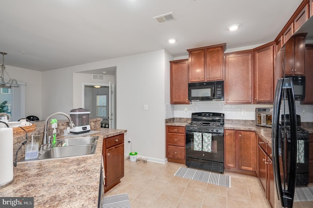 kitchen featuring decorative backsplash, light stone countertops, sink, and black appliances