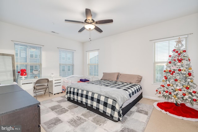 bedroom featuring multiple windows, ceiling fan, and light carpet