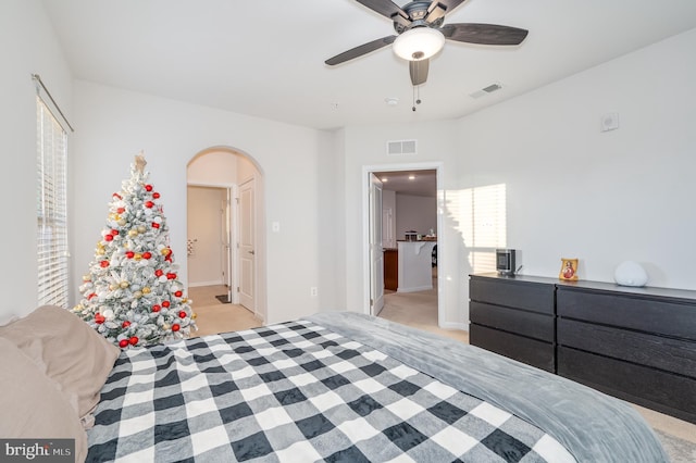 bedroom featuring ceiling fan, light colored carpet, and connected bathroom