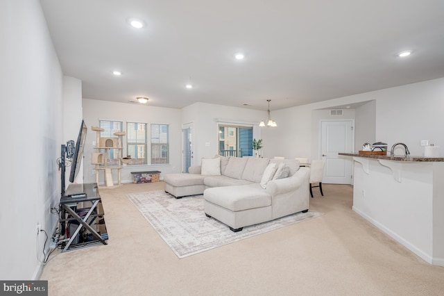 carpeted living room featuring sink and a notable chandelier