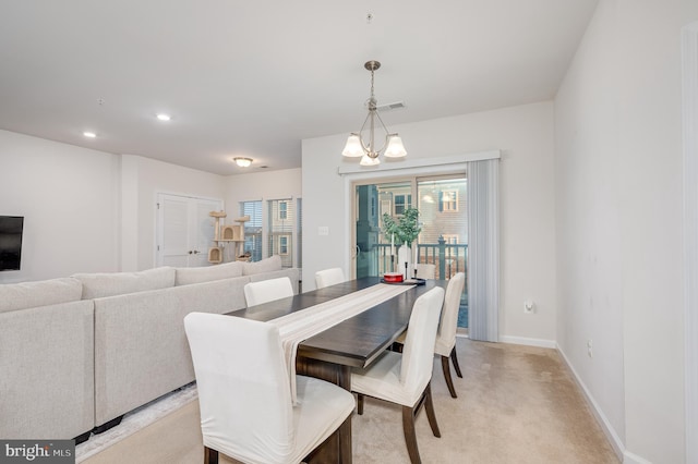 dining space featuring light colored carpet and a chandelier