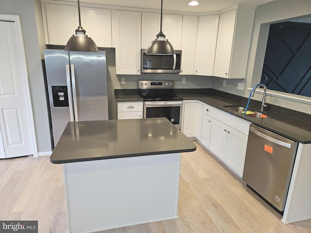 kitchen with pendant lighting, white cabinets, sink, light wood-type flooring, and appliances with stainless steel finishes