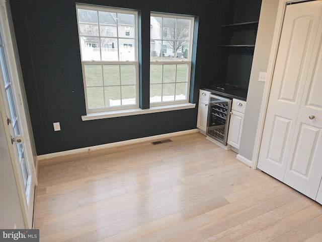 kitchen featuring white cabinetry, wine cooler, a wealth of natural light, and light hardwood / wood-style flooring