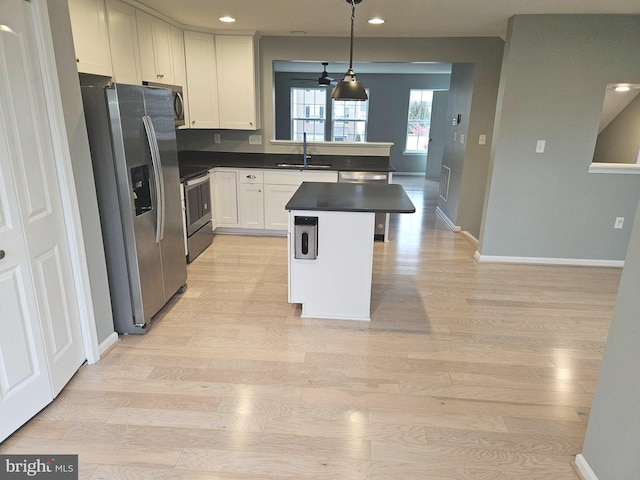 kitchen featuring appliances with stainless steel finishes, a kitchen breakfast bar, pendant lighting, white cabinets, and a center island