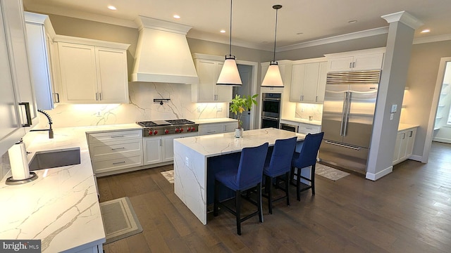 kitchen featuring custom exhaust hood, a center island, white cabinets, light stone countertops, and appliances with stainless steel finishes