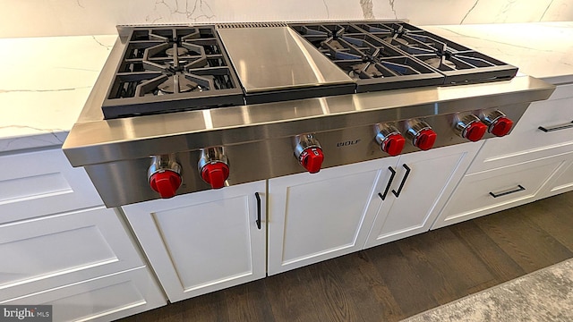 interior details featuring white cabinets, stainless steel gas stovetop, dark hardwood / wood-style flooring, and light stone counters