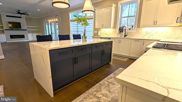 kitchen featuring sink, decorative light fixtures, white cabinetry, and light stone counters