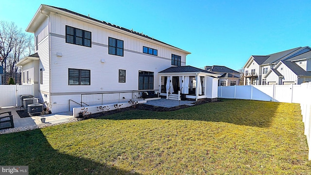 back of house with central air condition unit, a sunroom, a yard, and a patio