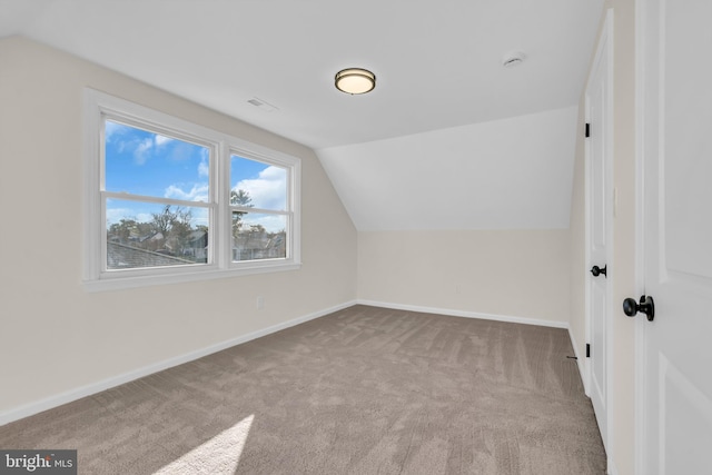 additional living space with light colored carpet and vaulted ceiling