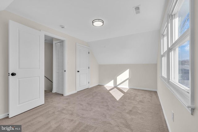 additional living space with light colored carpet, a wealth of natural light, and lofted ceiling