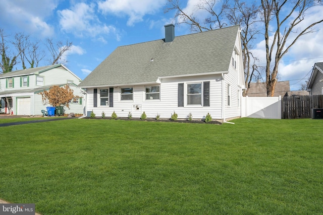 rear view of house featuring central air condition unit and a lawn