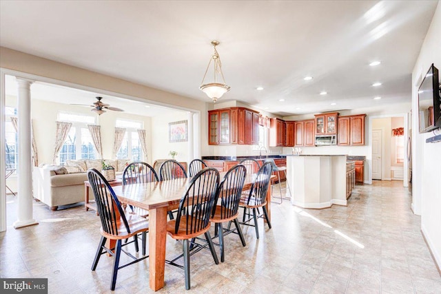 dining room with ornate columns, ceiling fan, and sink