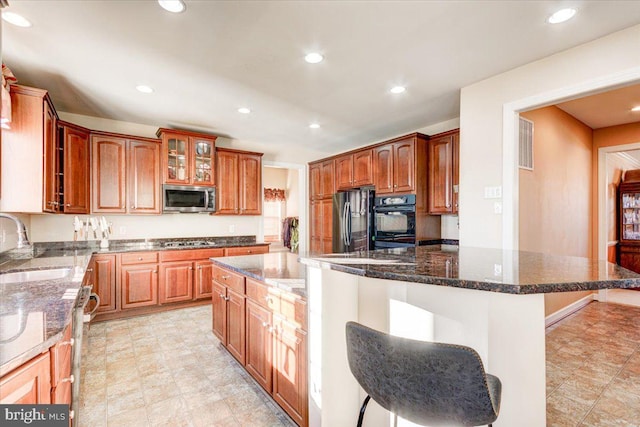 kitchen featuring dark stone countertops, a breakfast bar, a kitchen island, and stainless steel appliances