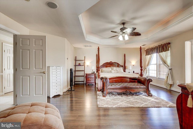 bedroom featuring a raised ceiling, ceiling fan, dark wood-type flooring, and crown molding