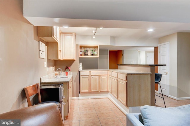 kitchen with a kitchen bar, kitchen peninsula, light brown cabinets, and light tile patterned flooring