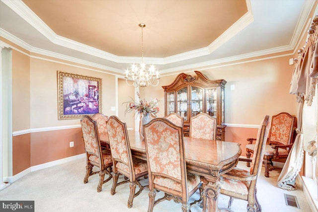 dining room featuring a raised ceiling, ornamental molding, light carpet, and a chandelier