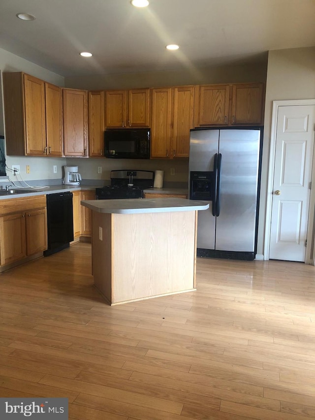 kitchen featuring a kitchen island, light hardwood / wood-style flooring, and black appliances