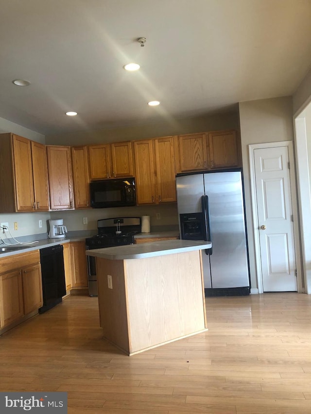 kitchen with light hardwood / wood-style flooring, black appliances, and a kitchen island