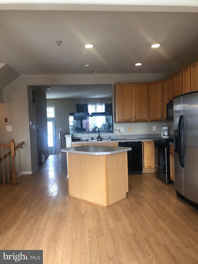 kitchen featuring sink, black appliances, light hardwood / wood-style floors, and a kitchen island