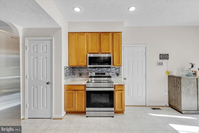 kitchen featuring tasteful backsplash, stainless steel appliances, and a textured ceiling