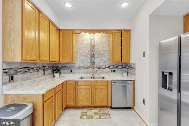 kitchen with light stone countertops, backsplash, stainless steel appliances, and sink