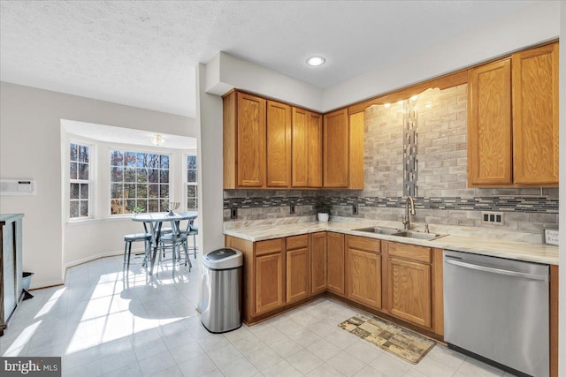 kitchen with stainless steel dishwasher, decorative backsplash, sink, and a textured ceiling