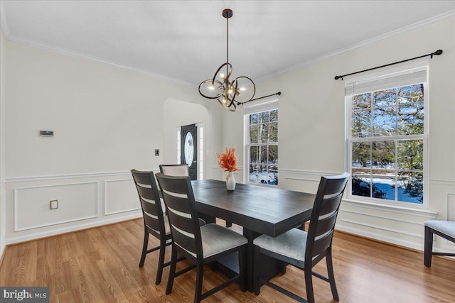 dining space featuring light wood-type flooring, crown molding, and a notable chandelier