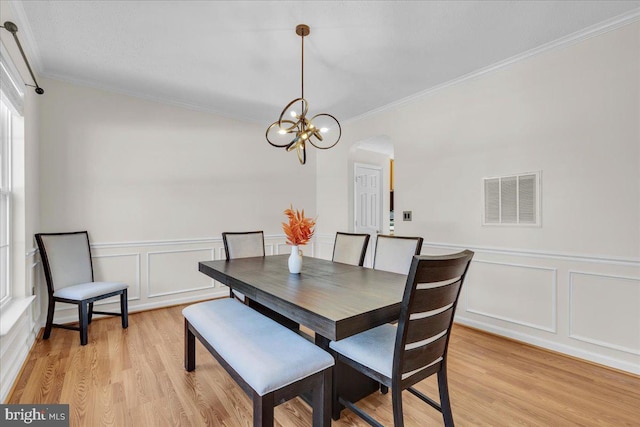 dining space with light hardwood / wood-style floors, crown molding, and a chandelier