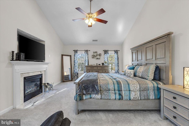 bedroom with ceiling fan, light colored carpet, a premium fireplace, and high vaulted ceiling