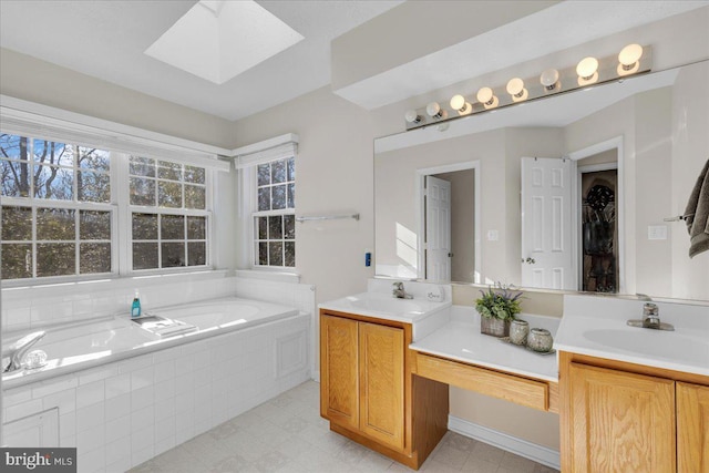 bathroom featuring a skylight, vanity, and tiled tub