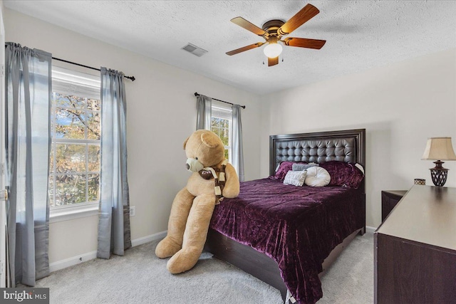 carpeted bedroom with ceiling fan and a textured ceiling