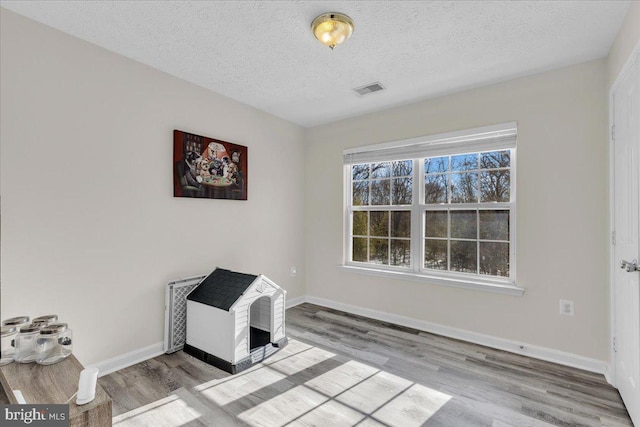 unfurnished room featuring light hardwood / wood-style floors and a textured ceiling