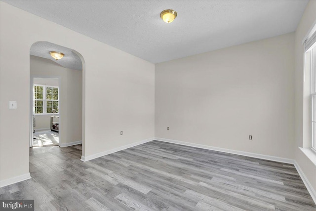 empty room with a textured ceiling and light hardwood / wood-style flooring