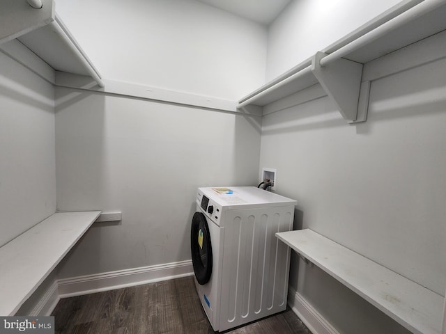 clothes washing area with washer / dryer and dark hardwood / wood-style flooring