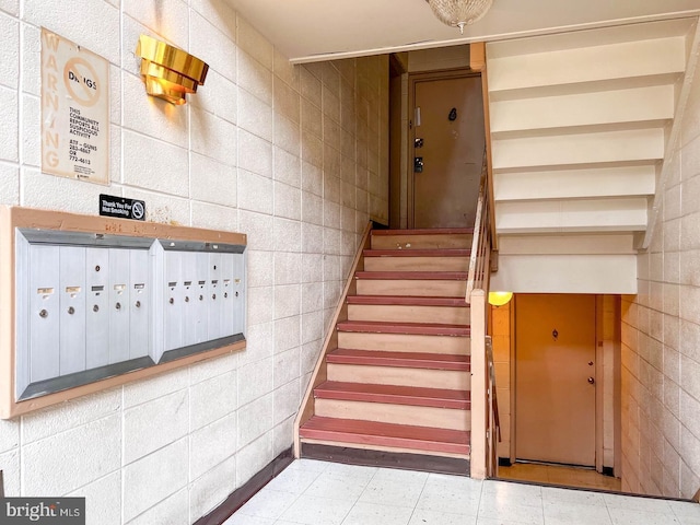 staircase featuring tile walls and a mail area